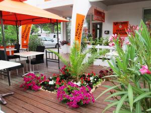 un restaurante con mesas y flores en una terraza de madera en Vittoria Immobilier 1- Vue dégagée - Terrasse - Chèques Vacances acceptés, en La Grande-Motte