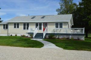 a white house with a porch and a red door at Carraig Dale Cottage in Fish Creek