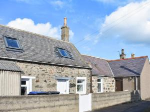 an old stone house with a stone wall at The Hobbit in Inverallochy