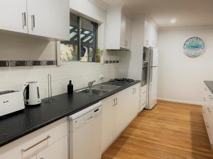 una cocina con armarios blancos y encimeras negras en Blue Tides Accommodation en Esperance