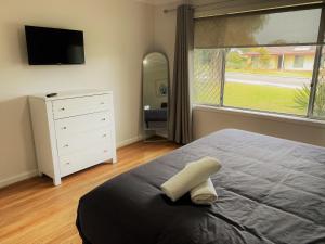 ein Schlafzimmer mit einem Bett, einer Kommode und einem großen Fenster in der Unterkunft Blue Tides Accommodation in Esperance