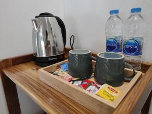 a wooden table with two coffee mugs and water bottles at Riddim Garden in Ko Samed