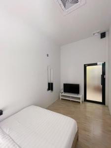 ein weißes Schlafzimmer mit einem Bett und einem Fernseher in der Unterkunft Paknap Hostel in Nan
