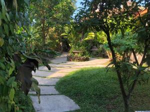 a garden path with a bench and trees at The Onion Collective in Ubud