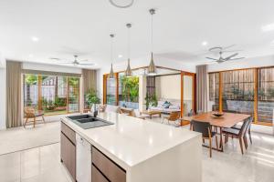een keuken en een woonkamer met een tafel en stoelen bij Belle Escapes Havenly Luxury Villa Palm Cove in Palm Cove