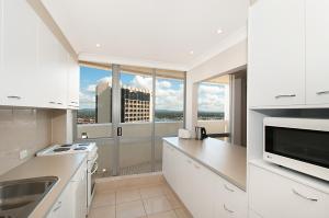 a white kitchen with a view of a building at Focus Apartments in Gold Coast