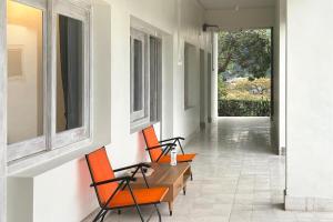 2 sillas naranjas y una mesa de madera en una habitación en Urbanview Wisma Nirwana Tretes by RedDoorz en Pasuruan