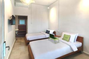 Habitación con 2 camas y una silla. en Urbanview Wisma Nirwana Tretes by RedDoorz en Pasuruan