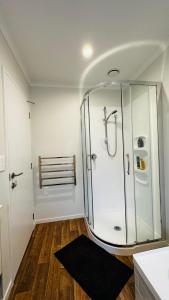 a bathroom with a glass shower with a black rug at Stay with the Singhs in Rolleston