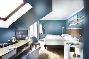 ein Schlafzimmer mit einem Bett und einem Schreibtisch mit einem Computer in der Unterkunft Hotel Liegeplatz 13 Kiel by Premiere Classe in Kiel