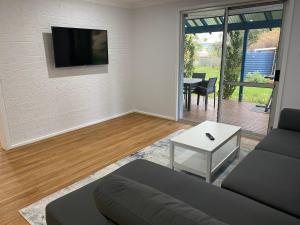 ein Wohnzimmer mit einem Sofa und einem TV an der Wand in der Unterkunft Blue Tides Accommodation in Esperance