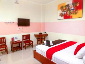 a bedroom with a bed and a tv and chairs at RedDoorz Near Jalan Jendral Sudirman in Manado