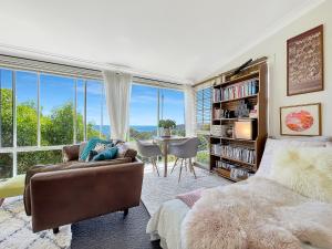 a bedroom with a bed and a couch and a table at Riversong & Sea Dreaming in Pambula Beach