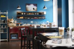ein Restaurant mit blauen Wänden, Tischen und Stühlen in der Unterkunft Hotel Liegeplatz 13 Kiel by Premiere Classe in Kiel