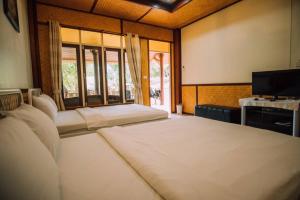 a room with two beds and a tv and windows at Baanpufa Resort in Sai Yok
