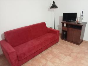 un divano rosso in un soggiorno con TV di alloggio del Viandante a Montefiascone