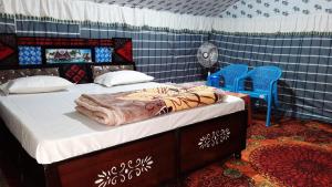 a bedroom with a bed and two blue chairs at DJSR Resort in Barkot