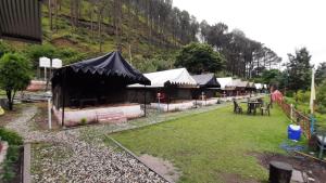 a row of tents with tables and chairs in a field at DJSR Resort in Barkot +55 photos