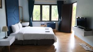 a bedroom with a white bed and a television at Central Backpackers Hostel - Phong Nha in Phong Nha +40 photos