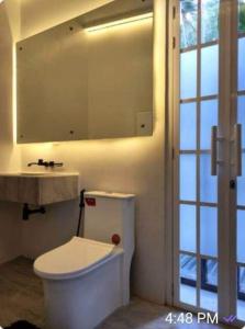 a bathroom with a toilet and a sink and a mirror at Puerto Galera Home in Balatero