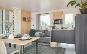 eine Küche und ein Wohnzimmer mit einem Sofa und einem Tisch in der Unterkunft Camping Le Village de la Mer in Les Moutiers