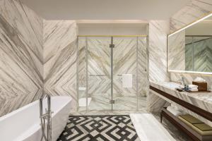 a bathroom with a shower and a tub and a sink at Indore Marriott Hotel in Indore