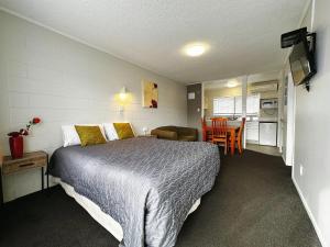 a bedroom with a bed and a kitchen and a table at Continental Motel in Whangarei