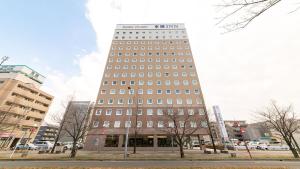 a tall building with many windows on a city street at Toyoko Inn Urawa misono eki Higashi guchi in Saitama