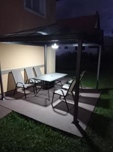 una mesa de picnic y sillas bajo una tienda por la noche en Guest House Toic, en Korenica