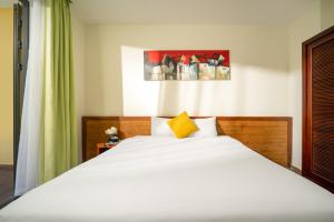 1 dormitorio con 1 cama blanca grande con almohada amarilla en Palm Boutique Village - STAY 24H en Hoi An