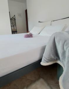 una cama blanca con una flor morada sentada en ella en FBM Anagenessis - Ευ Ζην en Edessa