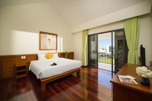 1 dormitorio con cama, escritorio y balcón en Palm Boutique Village - STAY 24H, en Hoi An