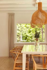 un comedor con una mesa con sillas y una ventana en Stylish villa 12p with private pool in the Veluwe en Garderen