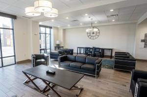 - une salle d'attente avec des canapés, une table et des chaises dans l'établissement Atrium Hotel and Suites DFW Airport, à Irving