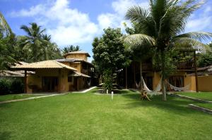 a resort with a yard with palm trees and a building at Pousada Porto da Barra in Barra Grande