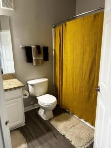 a bathroom with a toilet and a yellow shower curtain at Extravagant 2 BR/2 BA Apartment in Savannah