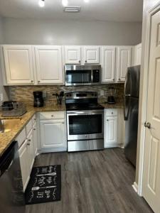 una cocina con armarios blancos y electrodomésticos de acero inoxidable en Extravagant 2 BR/2 BA Apartment en Savannah