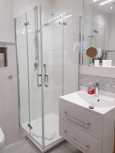 La salle de bains blanche est pourvue d'une douche et d'un lavabo. dans l'établissement Studio 6, Strandnah mit Balkon, à Sellin