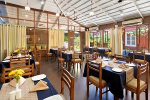 un restaurante con mesas y sillas azules y ventanas en Aldeia Santa Rita - Candolim, en Candolim