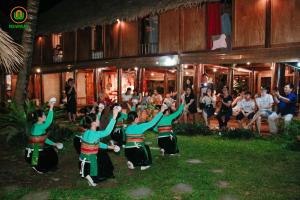 een groep mensen die voor een menigte dansen bij Pu Luong Thai House - Tai Dam Homestay in Hương Bá Thước