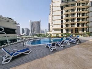 a row of lounge chairs and a swimming pool on a building at Dunya Tower Luxury and 2 min walk to Dubai Mall and Burj Khalifa in heart of Downtown in Dubai