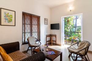 sala de estar con sofá, sillas y TV en Aldeia Santa Rita - Candolim, en Candolim