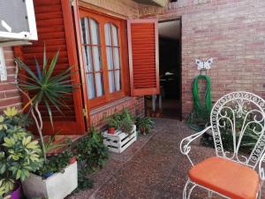 a porch with a white chair and some plants at La casa de Lily in Alta Gracia