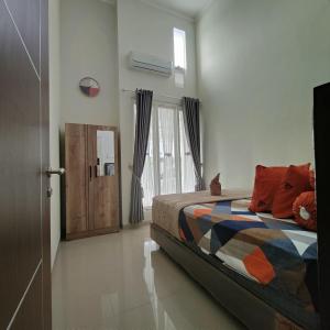 - une chambre avec un lit doté d'oreillers orange et une fenêtre dans l'établissement Kayana Regency F7, à Batu