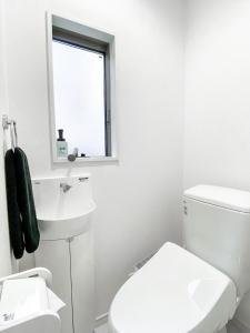 Baño blanco con aseo y lavamanos en FL Residence Takadababa - Vacation STAY 9959, en Tokio