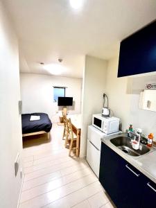 una pequeña cocina con fregadero y una habitación con cama en FL Residence Takadababa - Vacation STAY 9959, en Tokio
