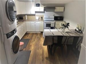 a kitchen with a table and a kitchen with white cabinets at Park side Basement 2 bedroom suite in Kelowna