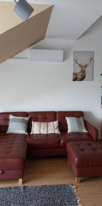 a red leather couch in a living room with a ceiling at Szarvas Apartman in Cserkeszőlő