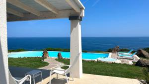 un patio con sedie, una piscina e l'oceano di Primaguadia Luxury Villa a Castelsardo