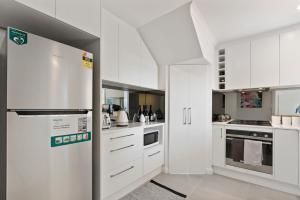 uma cozinha com armários brancos e um frigorífico em 13 47-48 Franklin Pde - Linen Included - Waterfront em Encounter Bay